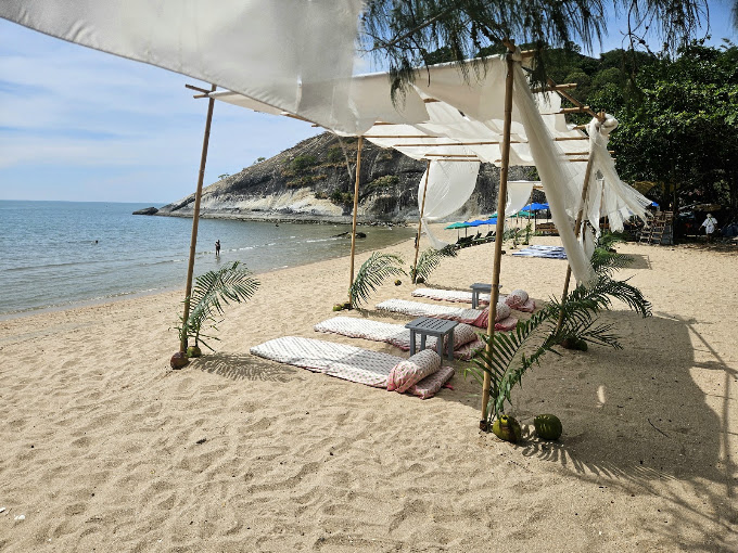Shaded beach loungers with cushions under a white canopy on the sand at Sai Noi Beach