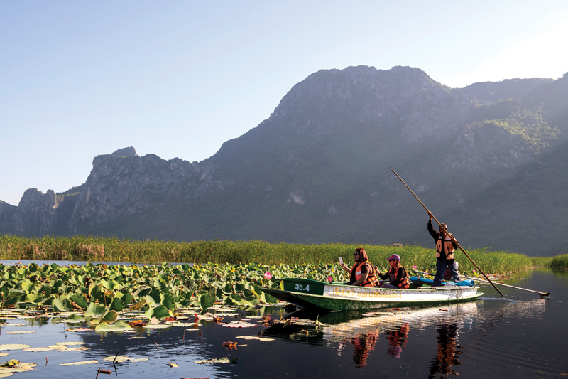 Small boat crossing the lotus-covered wetlands below the limestone peaks of Sam Roi Yot