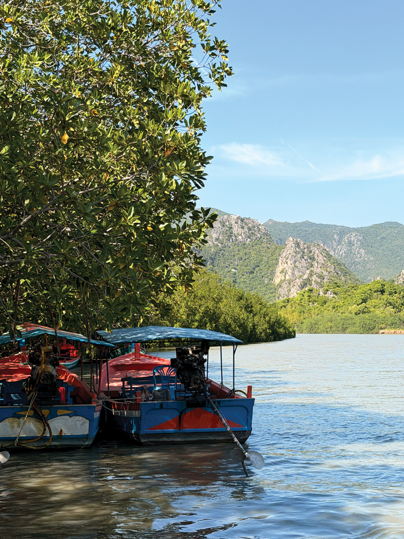 Mangrove-lined canal at Khlong Khao Daeng with limestone hills behind