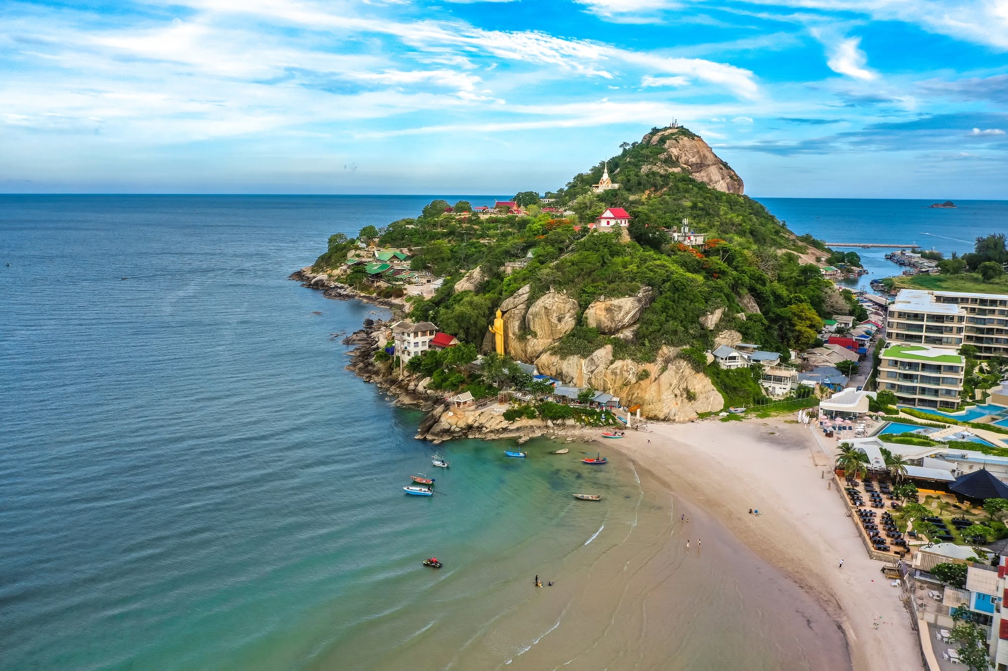 Aerial view of Khao Takiab headland with its golden Buddha, temple buildings and sandy beach curving into the Gulf of Thailand