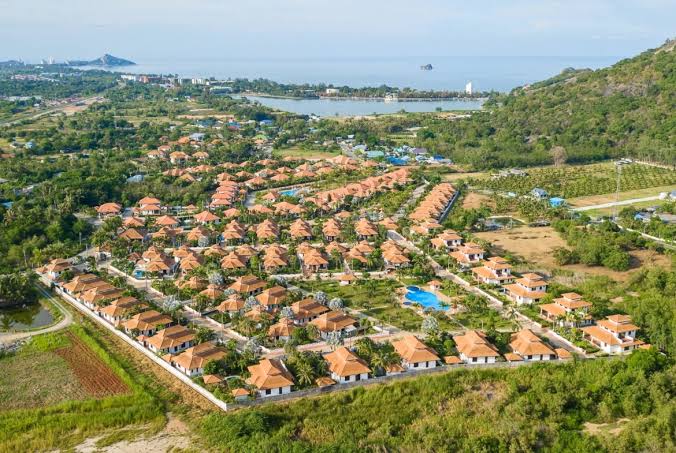 Aerial view of a Hua Hin residential neighbourhood with villas and the coast in the distance
