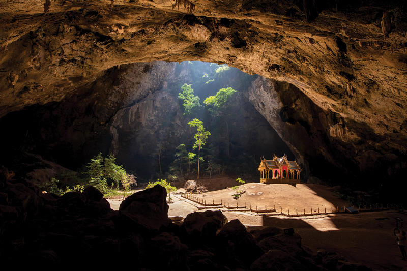 The golden royal pavilion inside Phraya Nakhon Cave, illuminated by a beam of sunlight from the cave roof