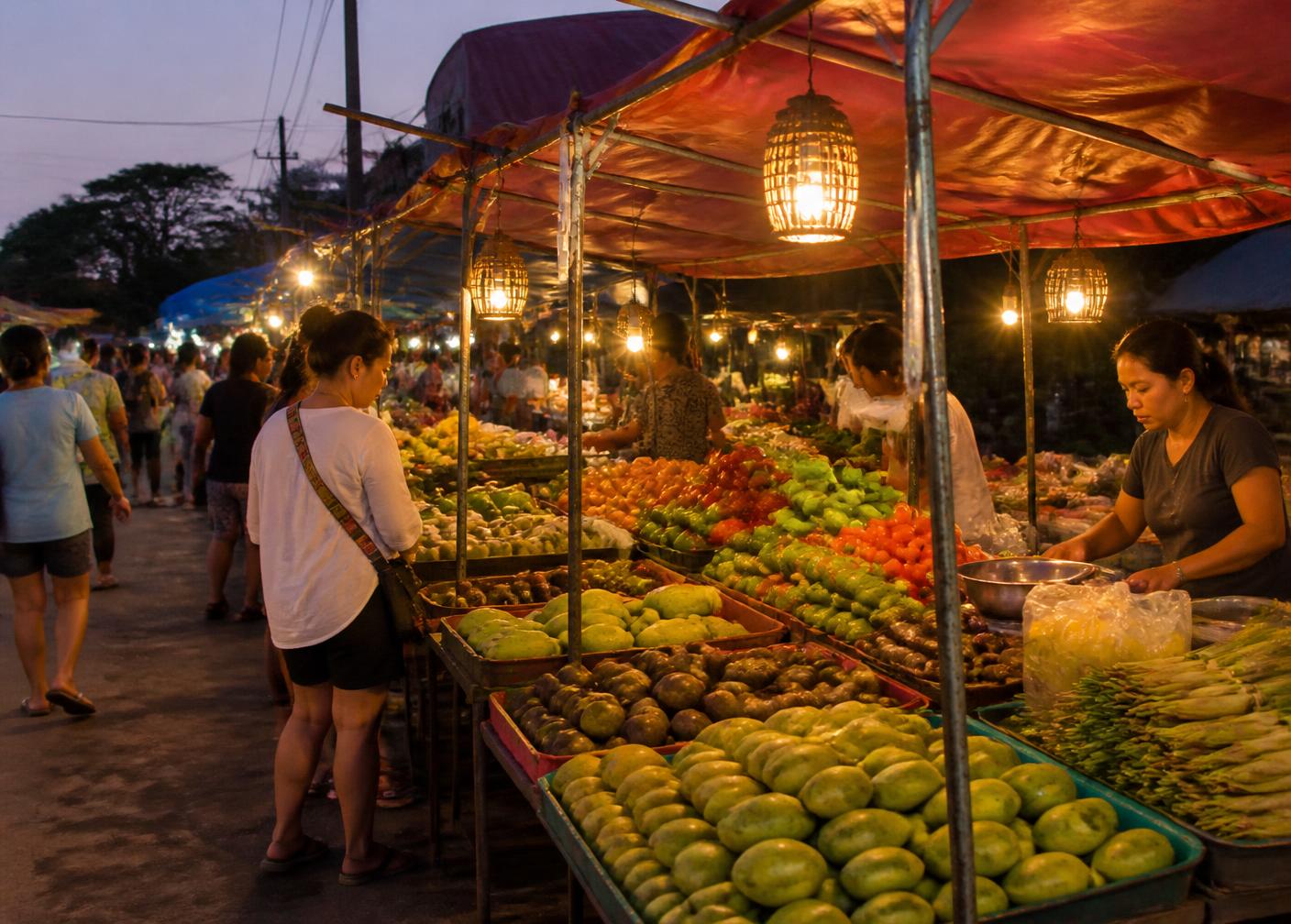 Evening fresh-food market in Hua Hin with fruit and vegetable stalls under warm lantern light