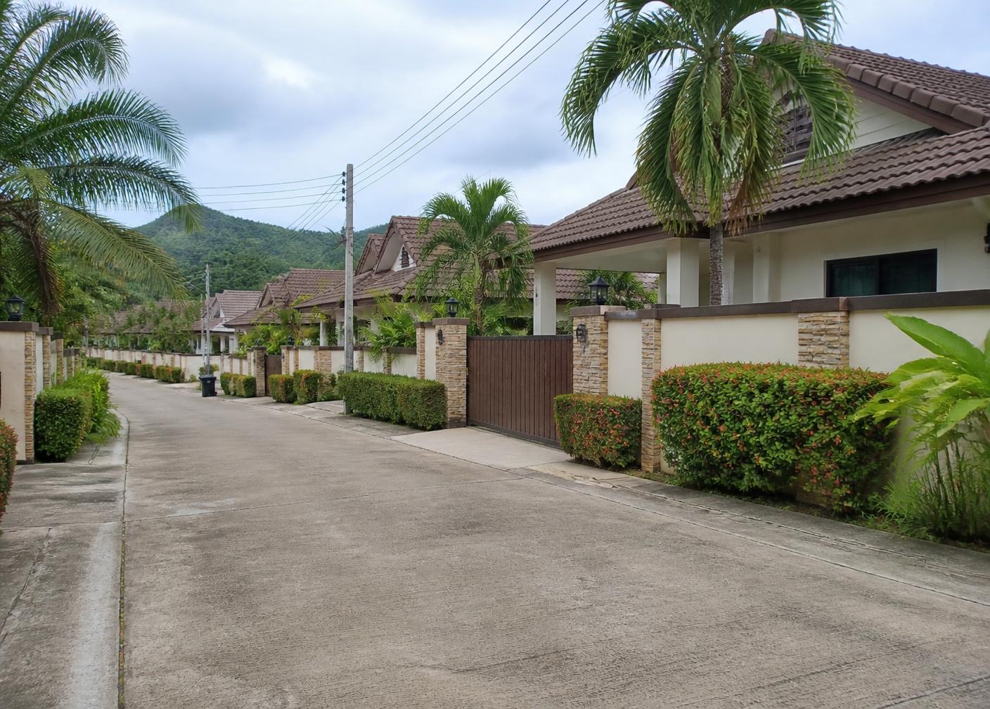 A quiet lane of single-storey villas with walled gardens in a Hua Hin residential development